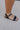 side view of female model wearing the Leila Daisy & Chain Double Anklet which features adjustable gold chain and daisy flower anklet