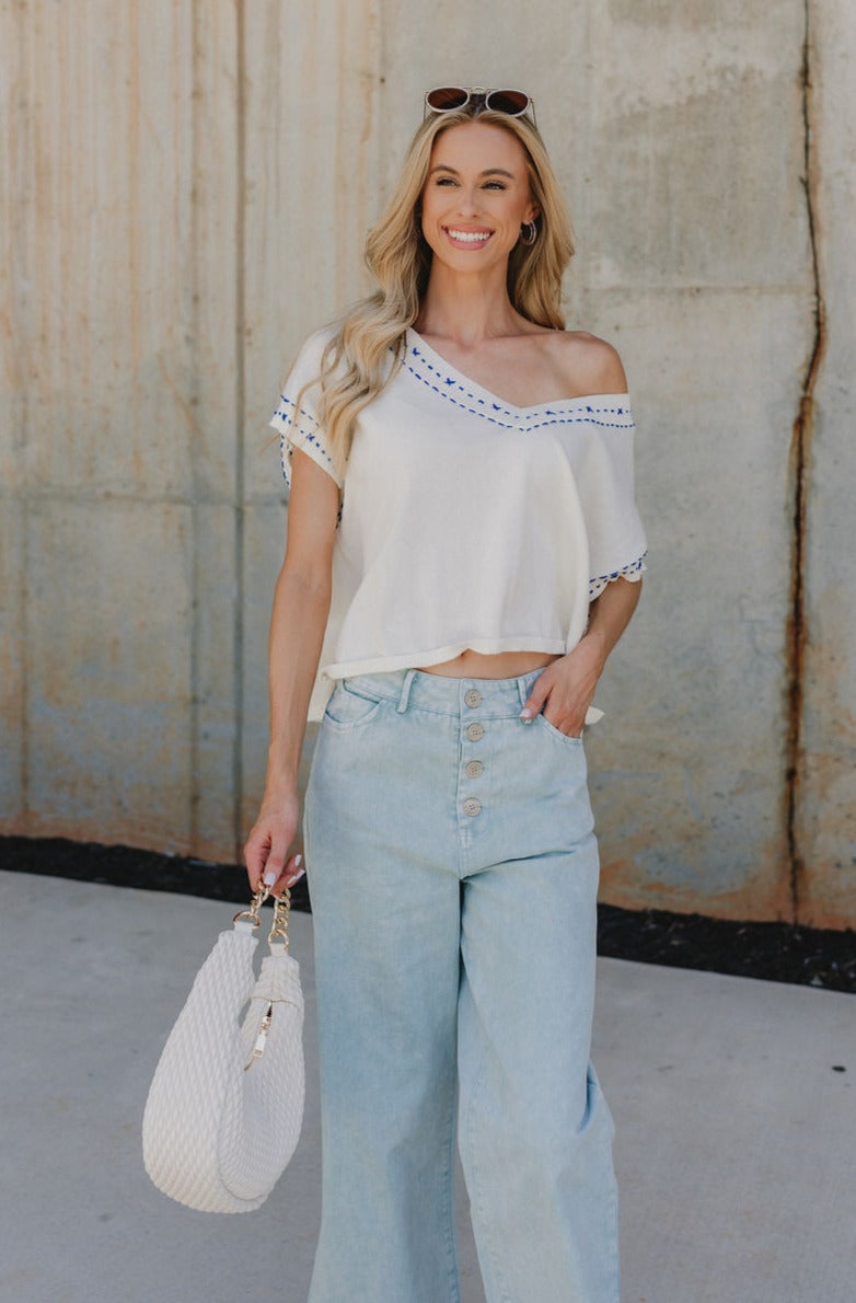 Front view of Marina Cream Short Sleeve Top with blue stitch details and a V neckline, with a wide length it's perfect for an off the shoulder look.