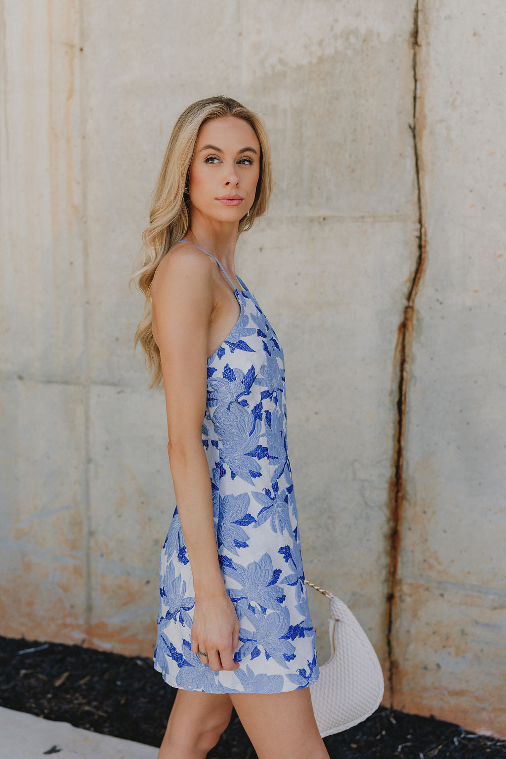 Side view of Blue Floral Mini Dress that has floral monochrome, white and blue, tied criss-cross  back, and spaghetti straps