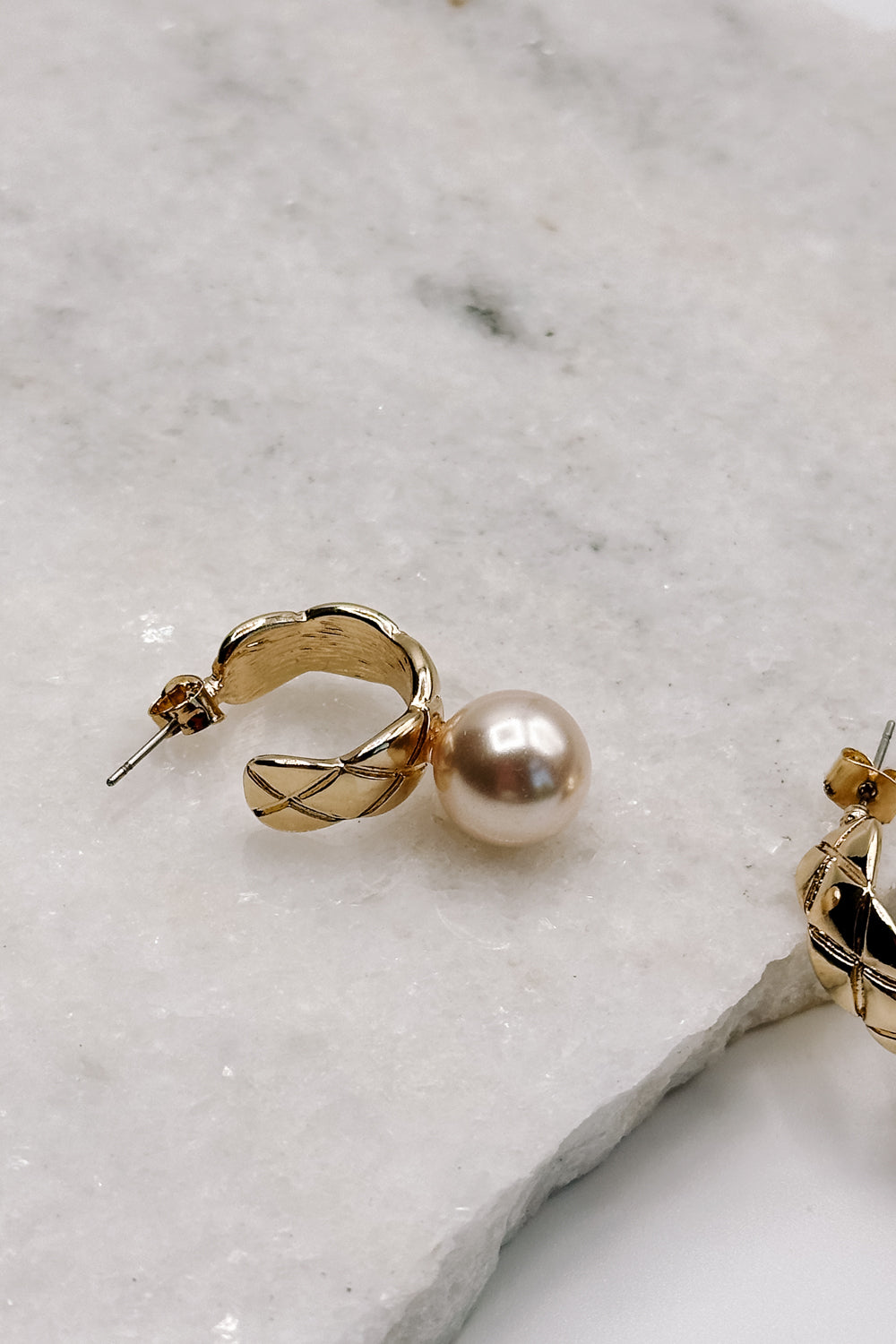 Close up view of the Skylar Pearl & Gold Hoop Dangle Earring which features gold braided mini hoops with pearl attachment