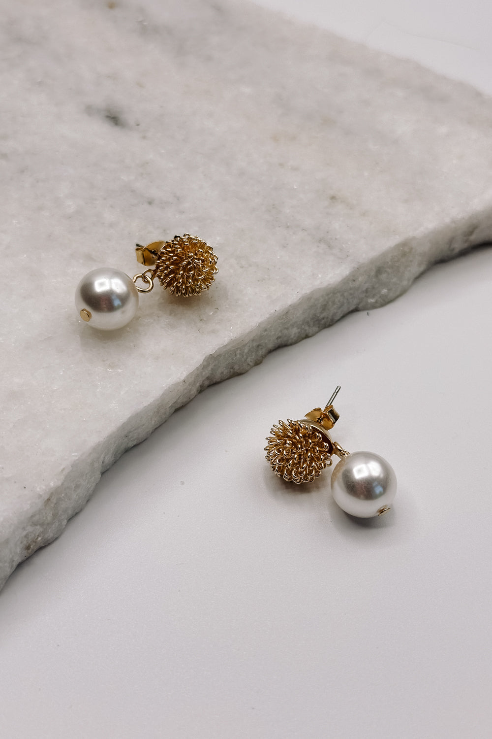 close up view of the Ayla Gold Speckle & Pearl Dangle Earring which features gold speckle flower stud with pearl dangle attachments