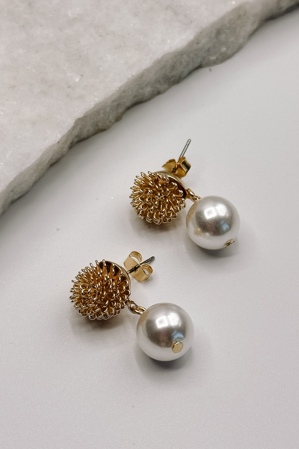 close up view of the Ayla Gold Speckle & Pearl Dangle Earring which features  gold speckle flower stud with pearl dangle attachments