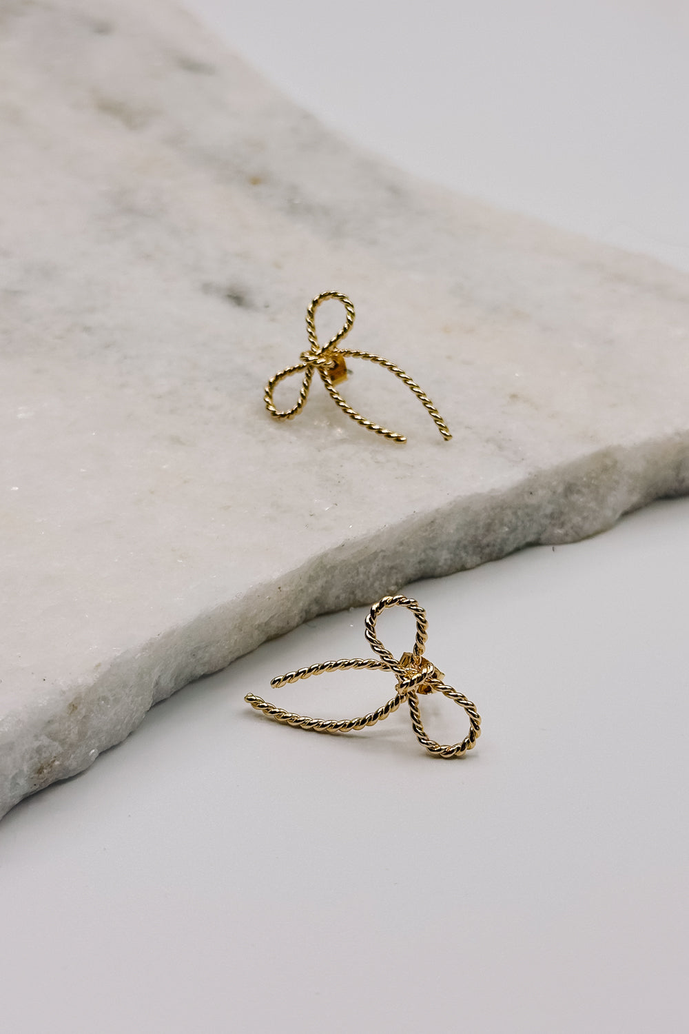 Close up view of the Alice Gold Roped Bow Stud Earring which features gold roped bow shaped studs
