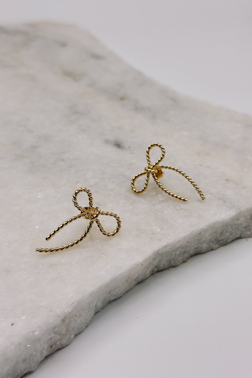 Close up view of the Alice Gold Roped Bow Stud Earring which features gold roped bow shaped studs