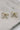 close up view of the Cora Gold & Pearl Bow Stud Earring which features gold bow shaped studs with light pink pearl beads