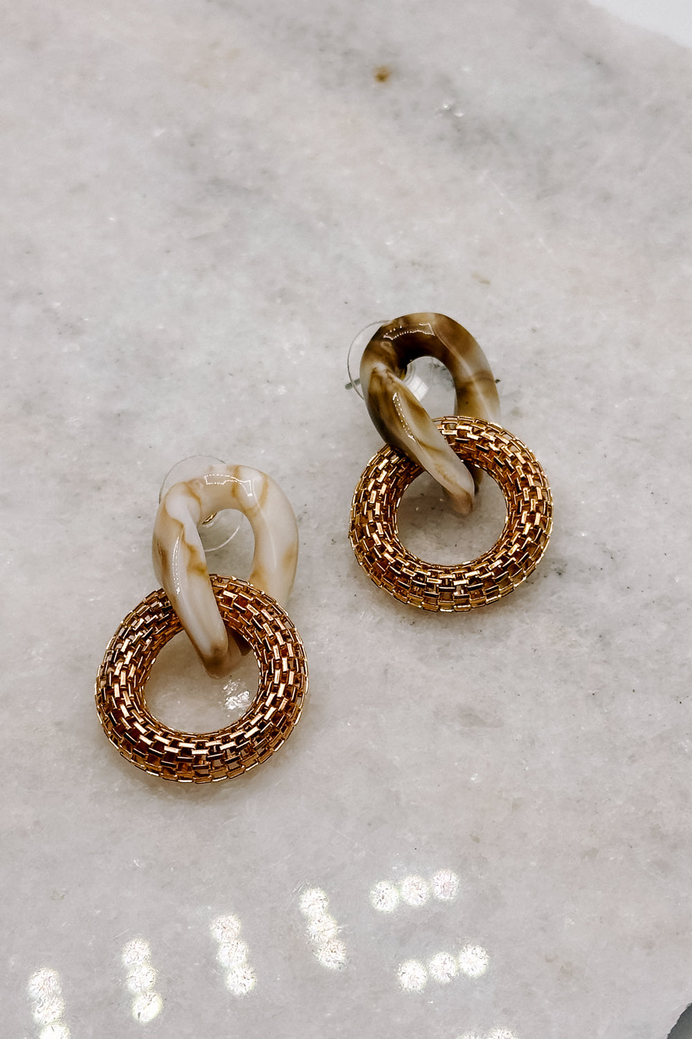 Front view of the Rhea Natural & Gold Dangle Earring which features  neutral tortoise chain linked to a gold ribbed chain