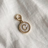 Image shows the 'C' alphabet charm against a white background. Charm is a gold circle with pearlescent center and has gold letter C in the center.
