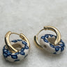 Close up of Lola White and Blue Pattern Link Earrings that are gold earrings with circle huggies that are a white and blue linked attachment