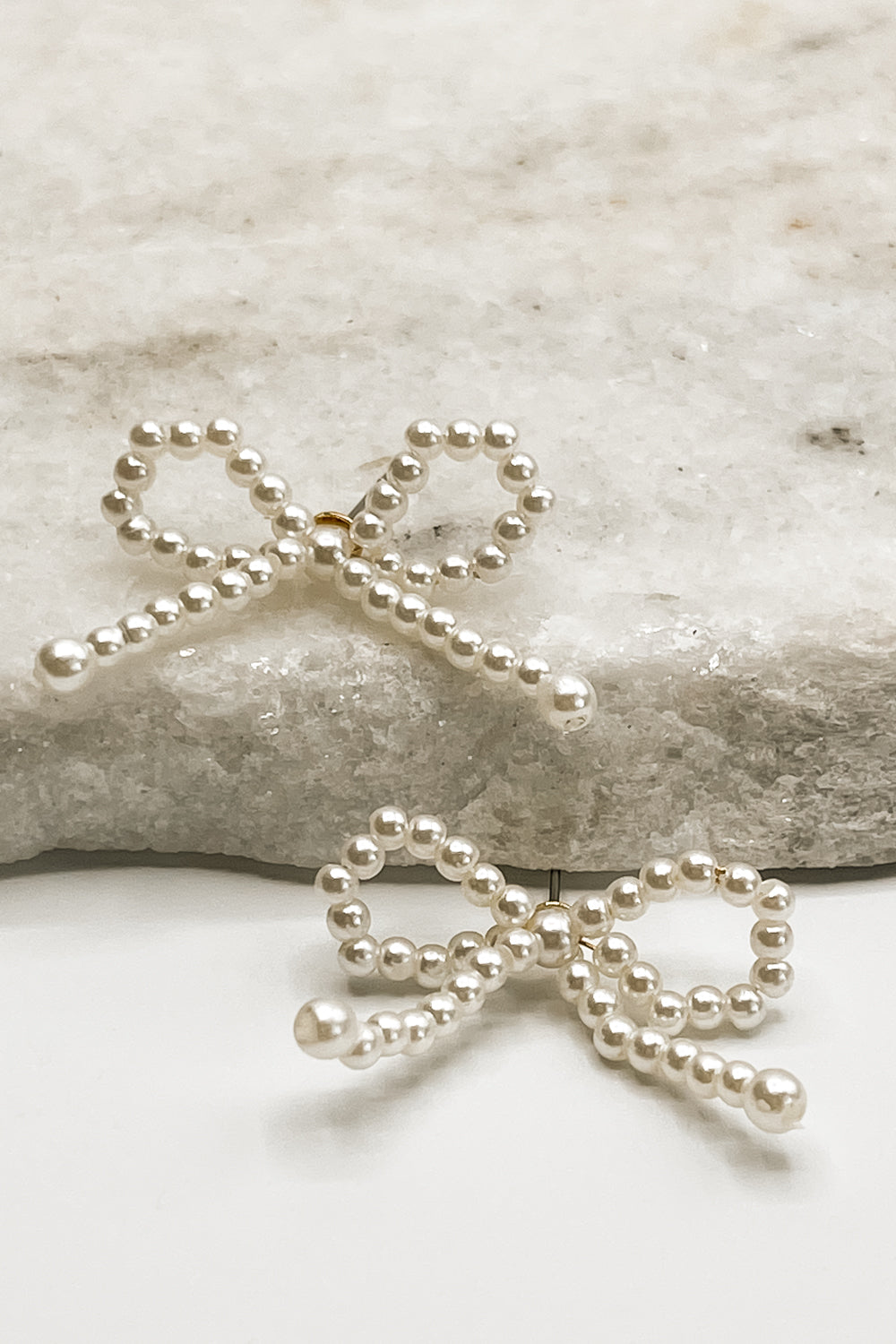 The Capri Bow Earrings lay against a neutral background.