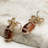  Close up of Callie Brown Rhinestone Football Earrings that are dangle earrings with rhinestone bows and footballs.