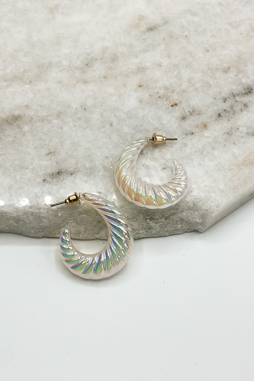 Close up of Eve Iridescent Hoops, white and iridescent ribbed hoops.