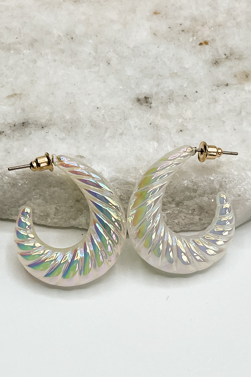 Close up of Eve Iridescent Hoops, white and iridescent ribbed hoops.