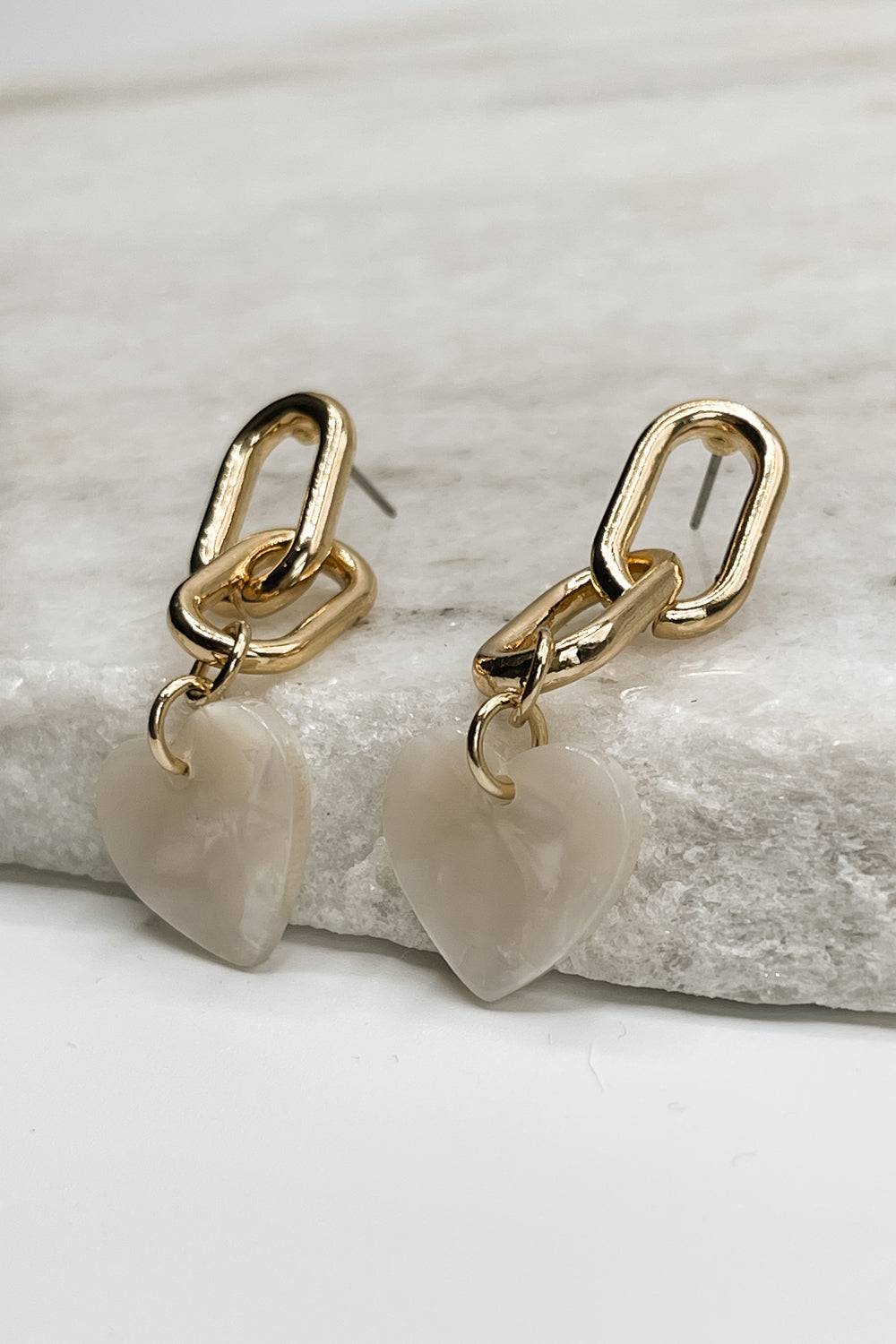 Image shows the Alia Gold Link & White Heart Earrings against a white background. Earrings have two gold chain links with a white marble heart pendant.