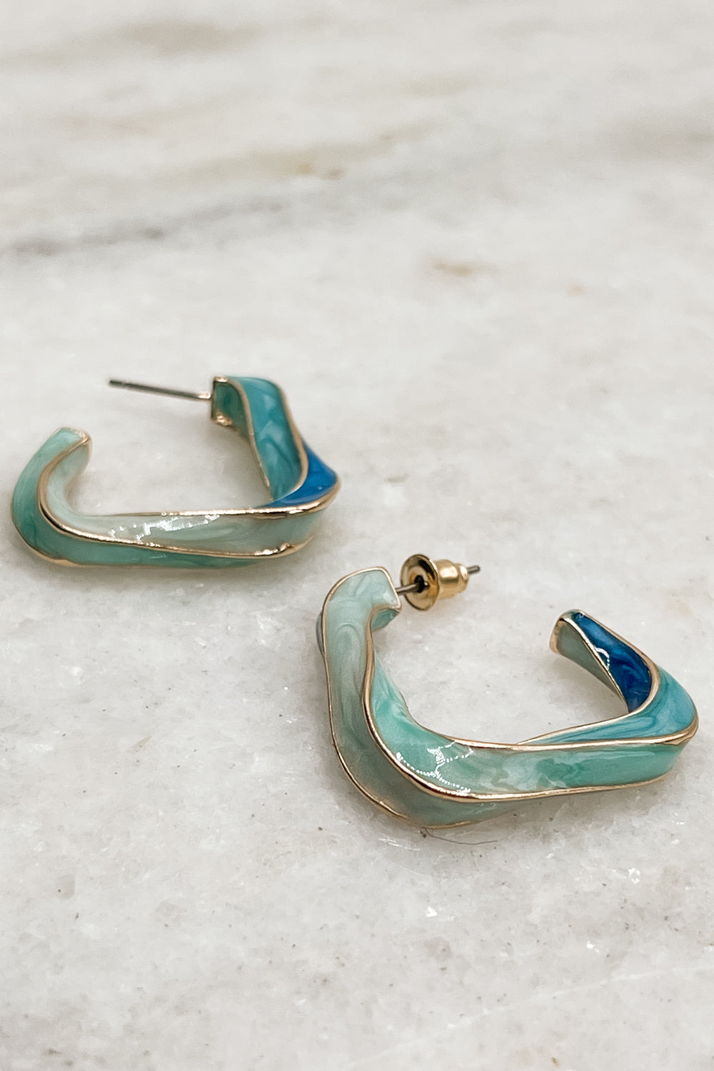 Alternate view of The Greyson Earrings are shown. They is gold and blue twisted hoops in a geometric shape.