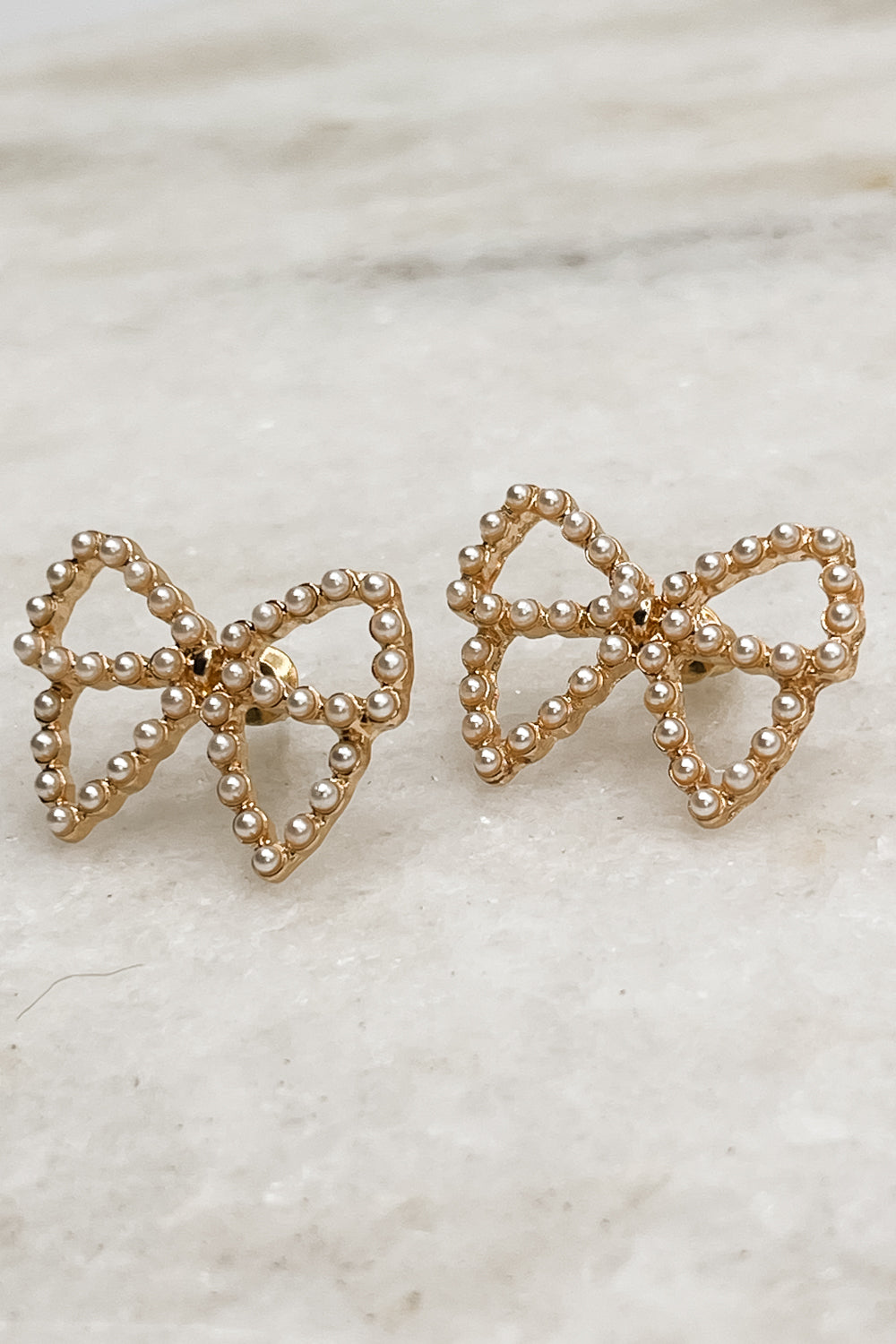 The Quincy Bow earrings sit against a neutral background.