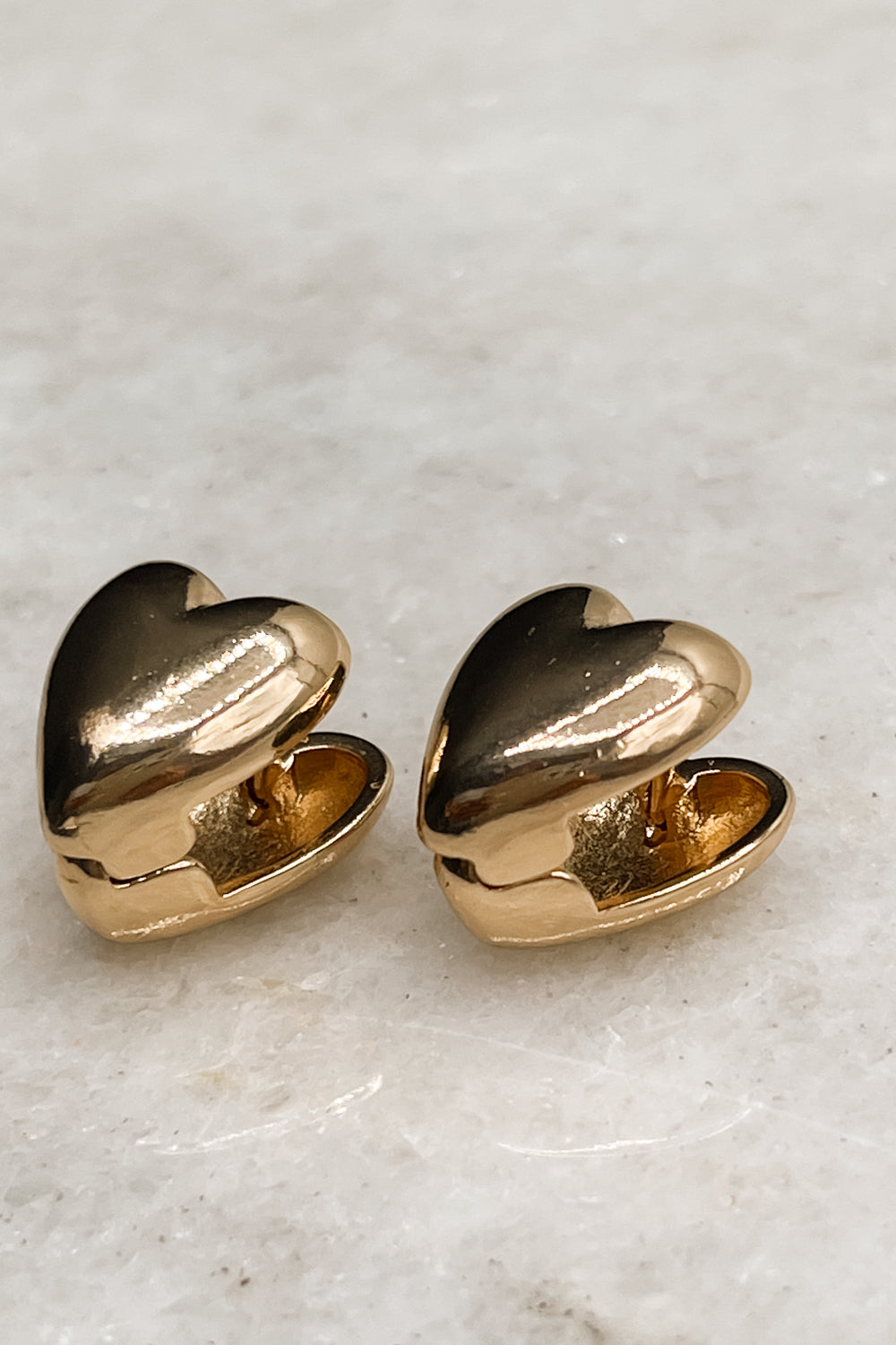 Alternate view of the The Raine Earrings is shown against a neutral background. They are gold heart-shaped studs.