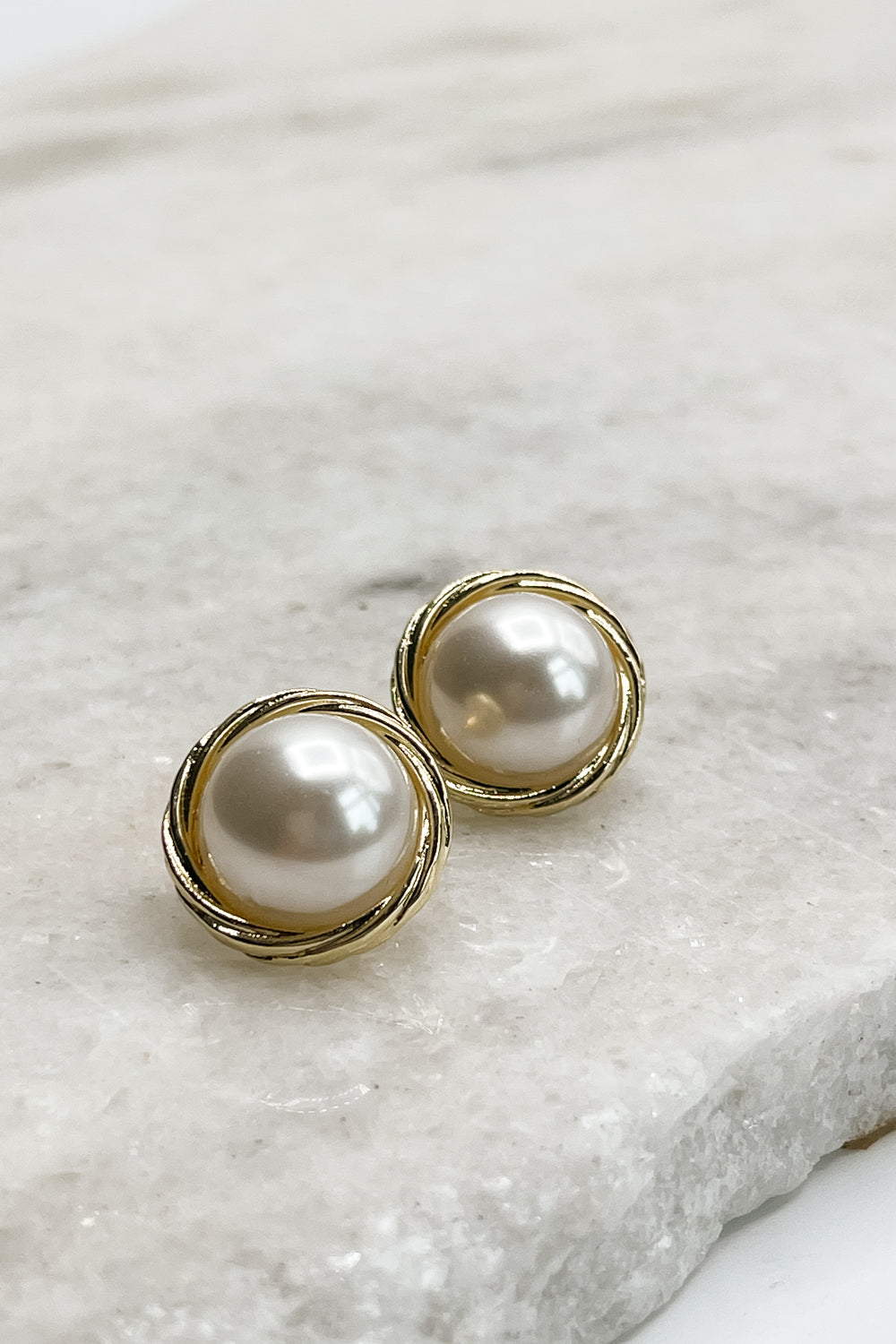 Close up of Camden Pearl Stud Earrings, pearl studs wrapped in gold.