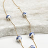 Close up of Amber White and Blue Floral Bead Earrings with a gold chain link 