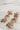 Earrings shown laid on a neutral background. They are dangle earrings with three red, white, & blue firework-shaped charms. 