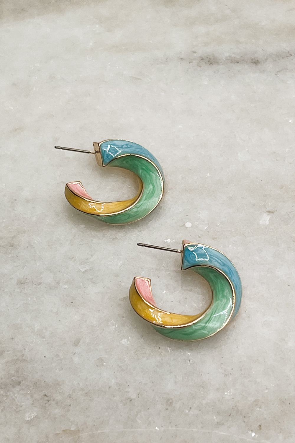 Earrings are shown on a neutral background. They are twisted hoops with blue, pink, yellow-orange, and green accents.