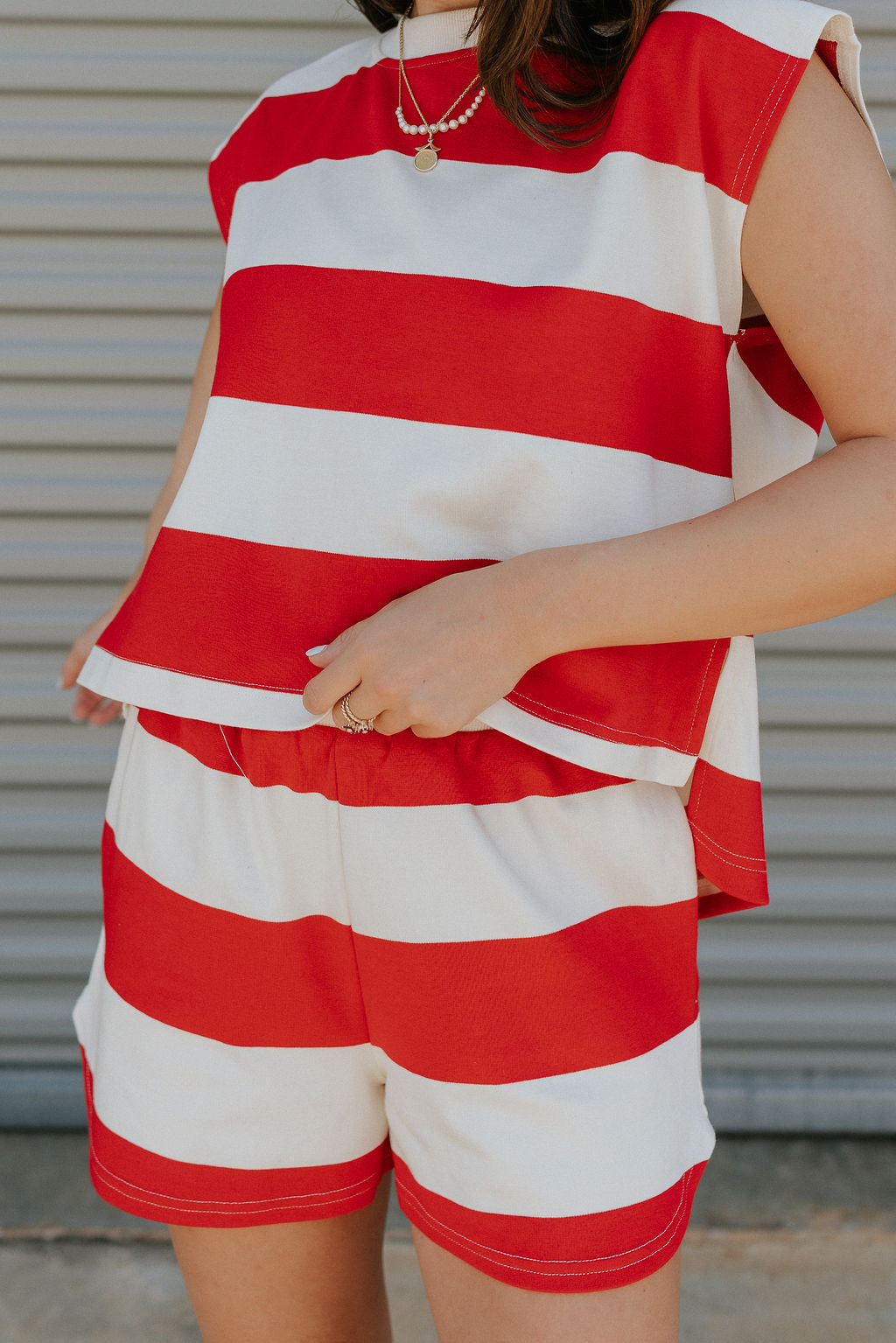 close up view of female model wearing the Bristol Red & White Stripe Sleeveless Top which features Red and Cream Stripe Lightweight Fabric Slits on the side, Round Neckline and Sleeveless