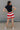 back view of female model wearing the Bristol Red & White Stripe Shorts which features Red and Cream Stripe Lightweight Fabric, Cream Lining, Elastic Waistband and Pockets on each side