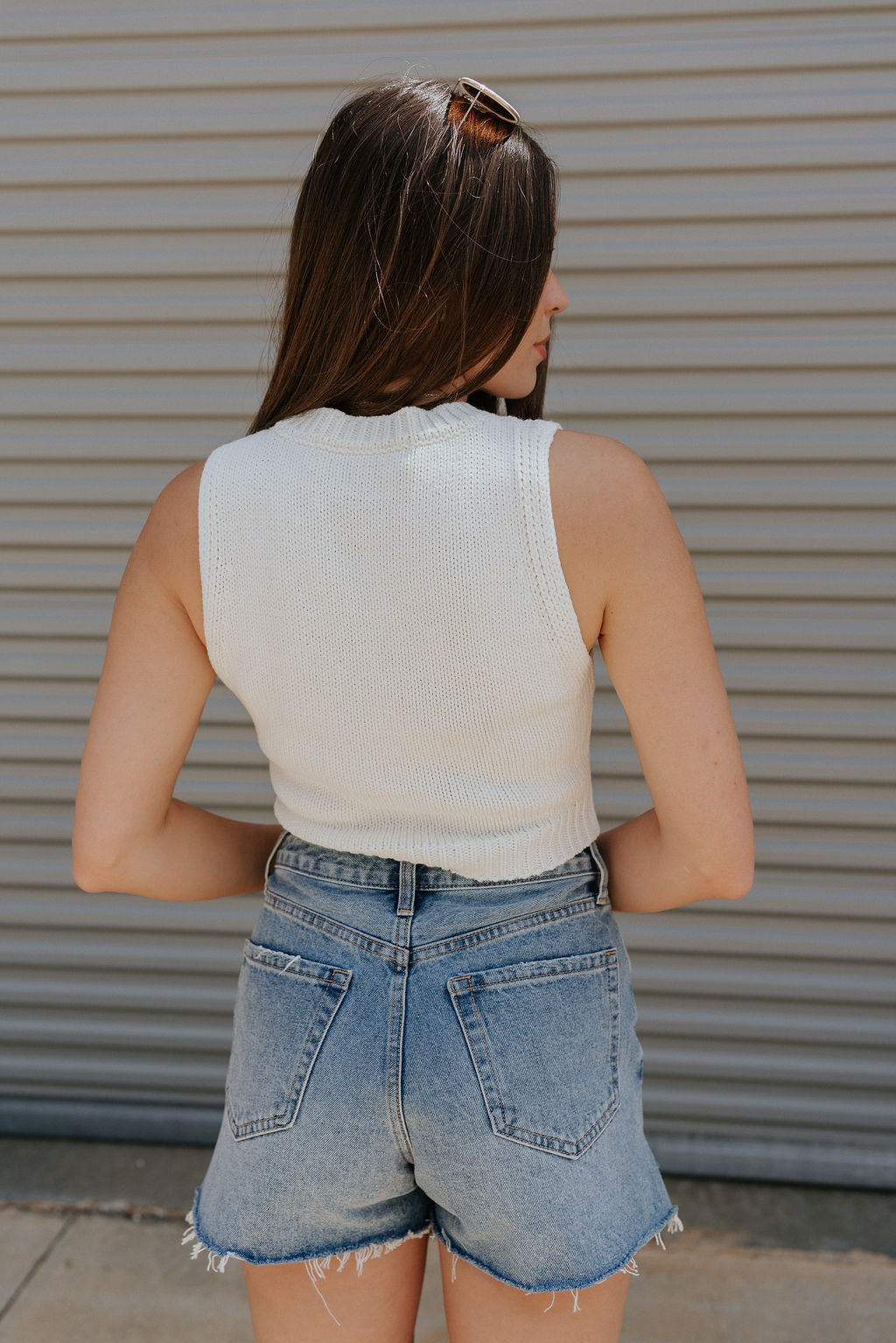 back view of female model wearing the Love America Cream Knit Tank which features Cream Knit Fabric, Round Neckline, Sleeveless and Red Stitch Heart, Says America in blue stitch writing