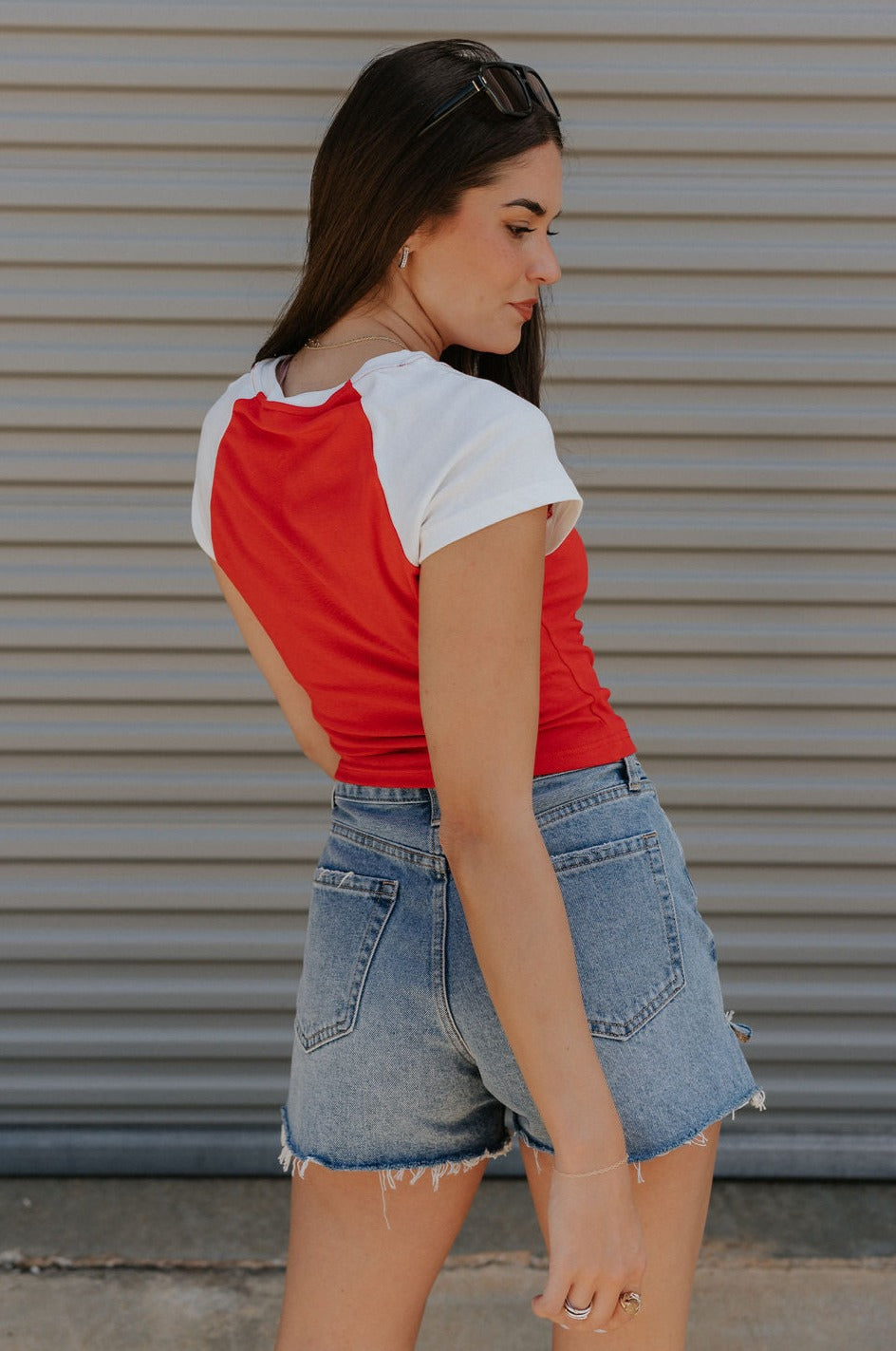back  view of female model wearing the USA Red & White Short Sleeve Top which features Red and White Lightweight Fabric, Color Block Pattern, Round Neckline, Short Sleeves and USA graphic stitch design