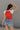 back view of female model wearing the USA Red & White Short Sleeve Top which features Red and White Lightweight Fabric, Color Block Pattern, Round Neckline, Short Sleeves and USA graphic stitch design