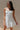 front view of female model wearing the Faye White Floral Ruffle Mini Dress which features White Lightweight Fabric, Monochrome Floral & Paisley Design, Ruffle Hem Skirt, White Shorts Lining, Sweetheart Ruffle Neckline, Adjustable Straps and Monochrome Back Zipper with Hook Closure