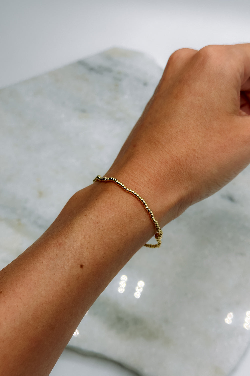 Image shows Jane Gold 2mm Beaded Water Resistant Bracelet on model's wrist.