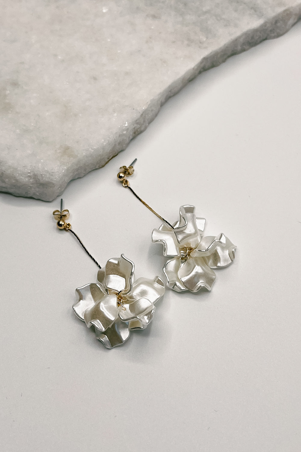 Close up of Elle White and Gold Flower Earrings, gold dipped strands with white ruffle flower petals.