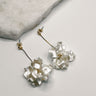 Close up of Elle White and Gold Flower Earrings, gold dipped strands with white ruffle flower petals.