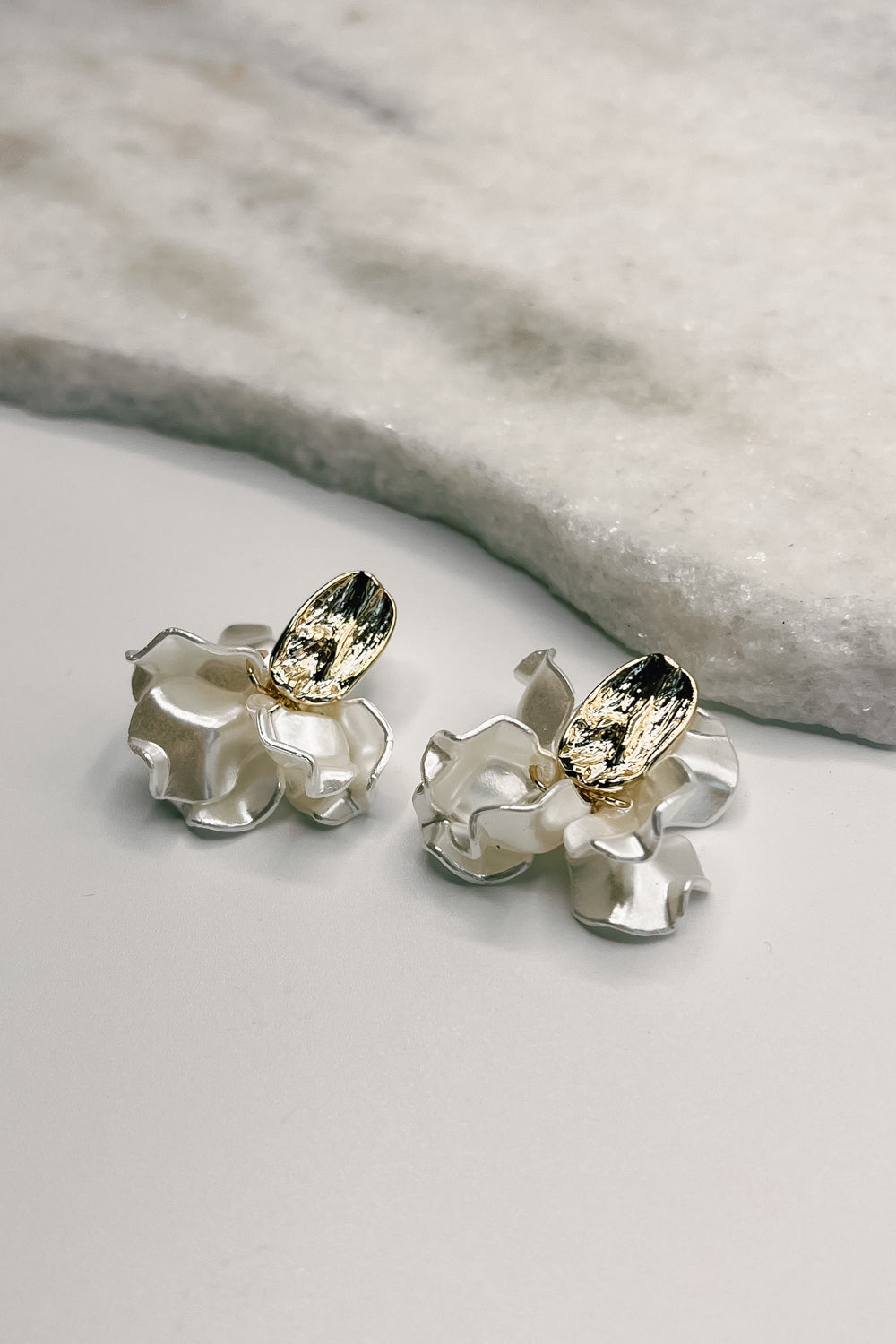 Close up of Hailey Gold and White Flower Earrings, gold dipped hammered studs with white ruffle flower petals.