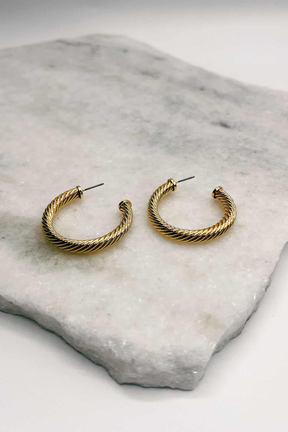 Close up of Brynn Gold Ribbed Hoops, open medium hoops.