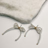 Close up of Aubrey Pearl Bow Earrings, pearl shaped bow stud earrings.