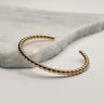 Close-up of the Lori Bangle bracelet. The gold brass bangle features beads and is designed to slip on easily.