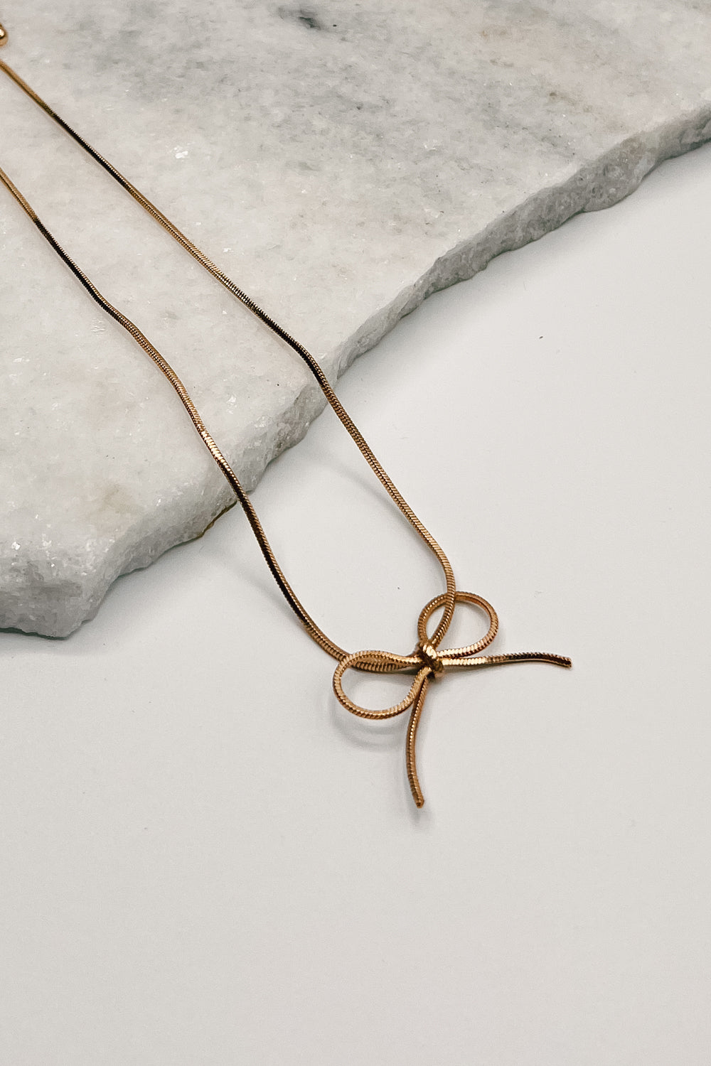 Close up of Brooklyn Gold Bow Necklace, adjustable gold necklace with a bow detail.