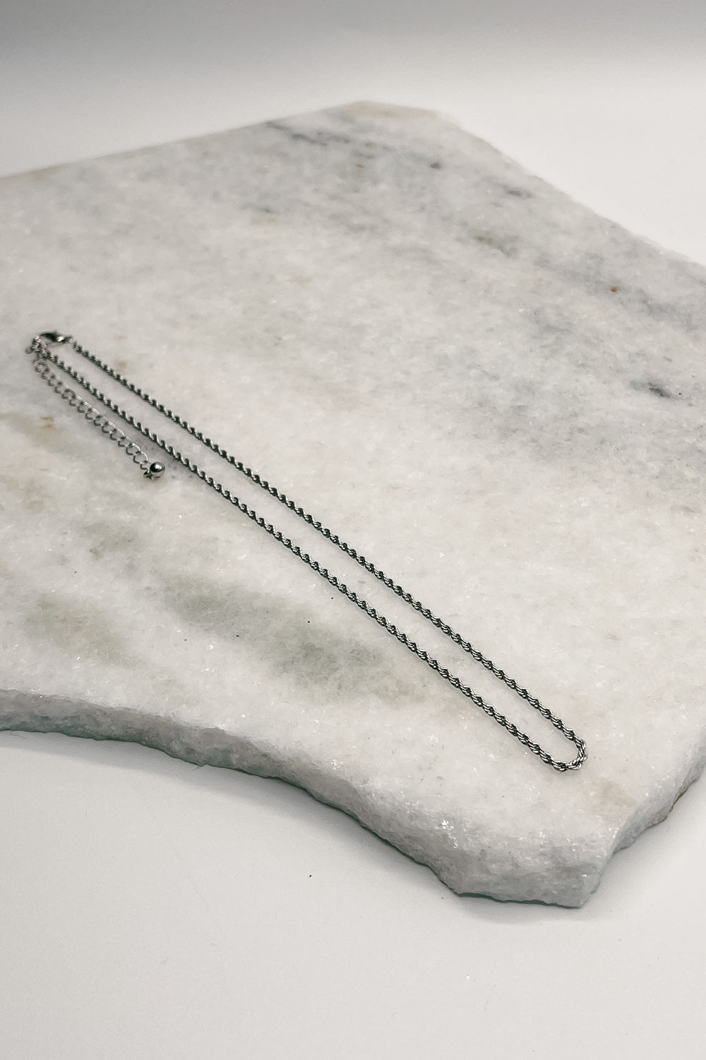 flat lay view of the Ellis Silver Twisted Rope Necklace which features single layer silver rope adjustable necklace