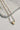 Image shows the Daphne Gold Heart Pearl Necklace against a marble background. Necklace has white pearl beads with small gold beads in between and a gold heart bead in center