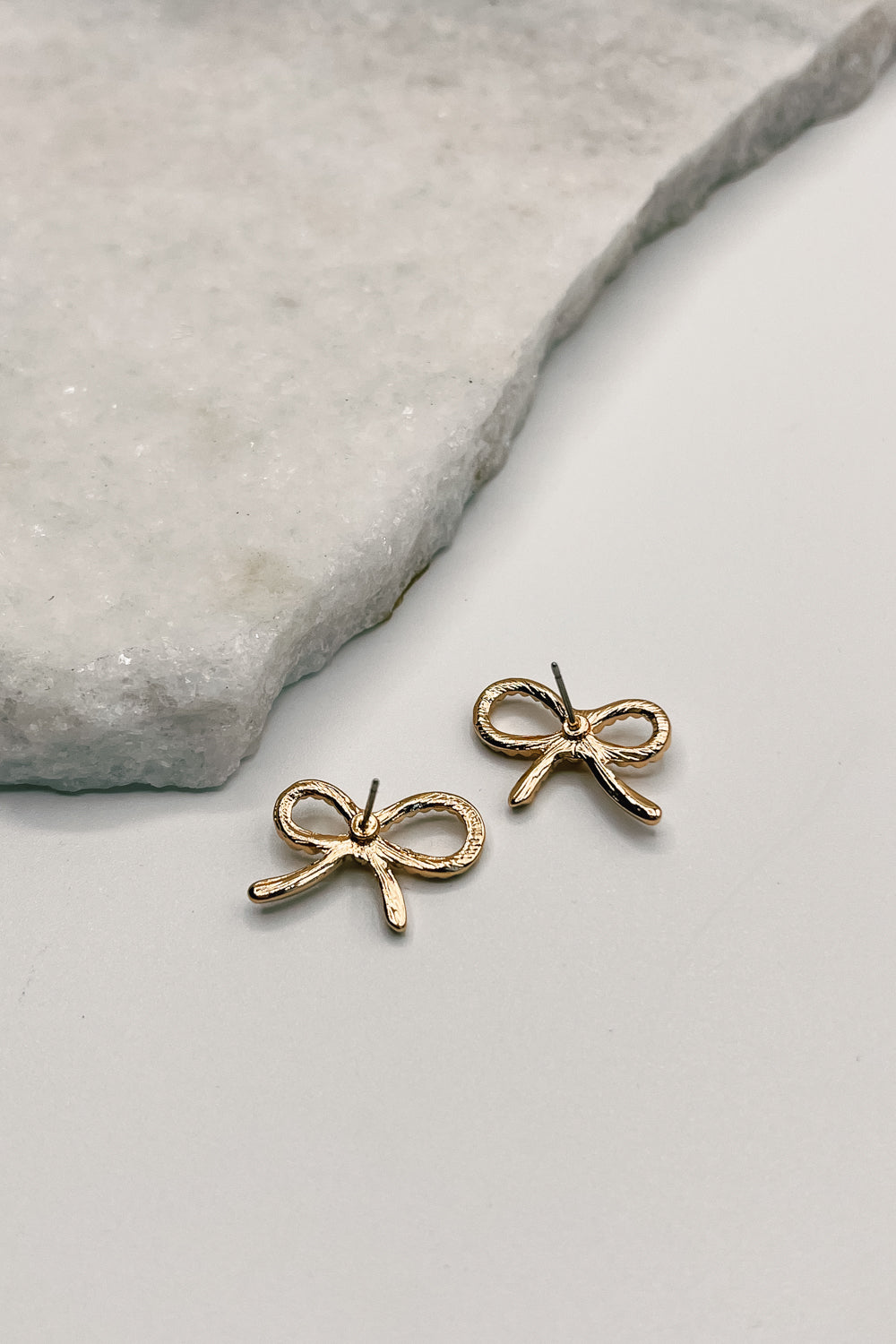 Close up of back of London Gold Ribbed Bow Earrings, gold ribbed bow shaped stud earrings.