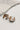The photo shows the Meg earrings lying on a neutral background.
