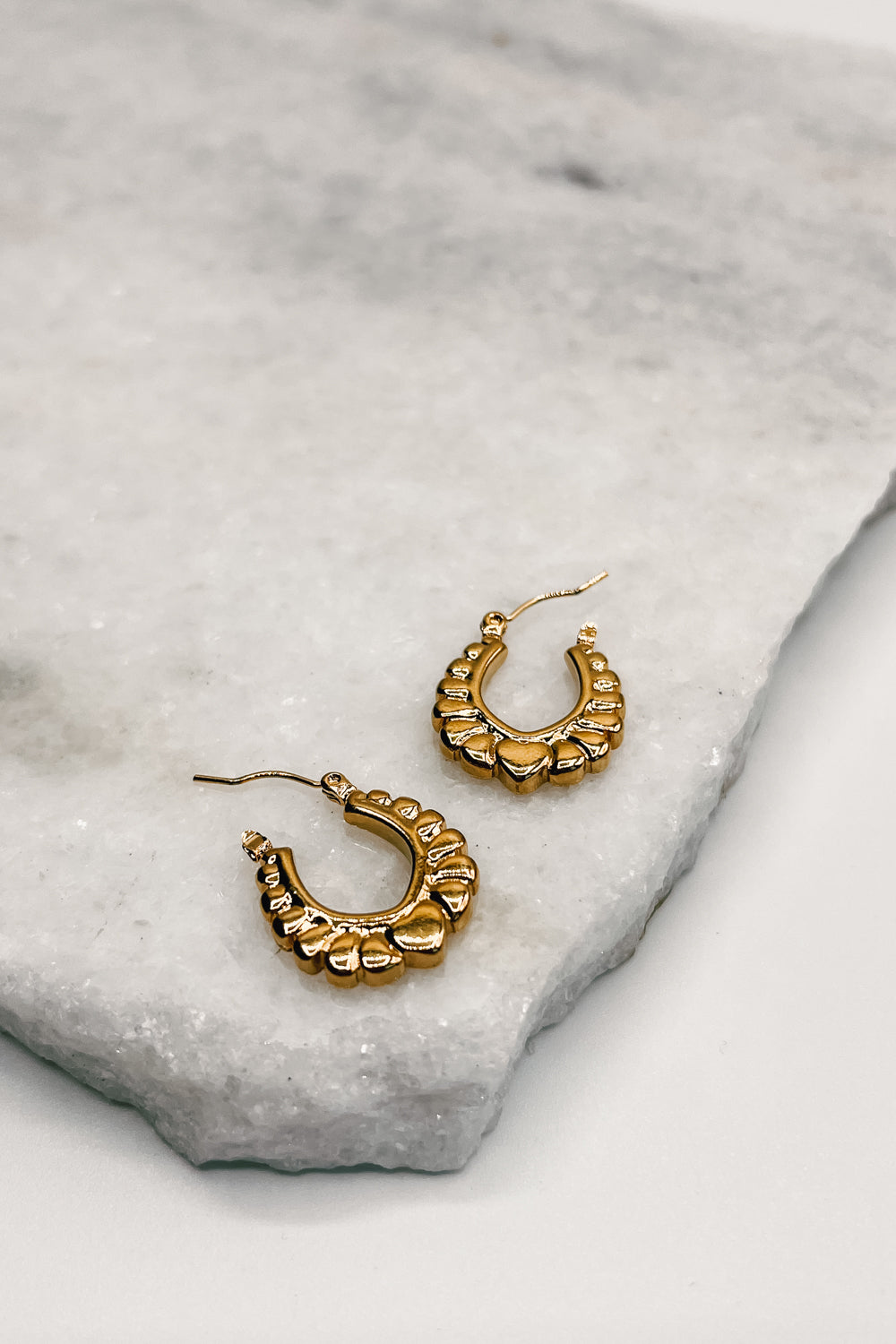 Close up of Blaire Gold Scalloped Hoops, gold scalloped mini hoops with heart detail.