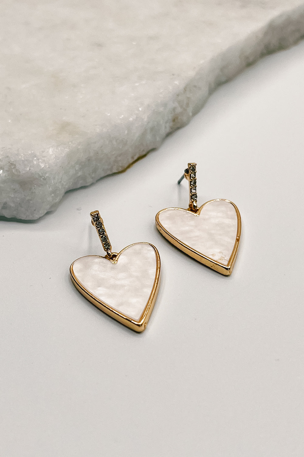 Close up of Emerson Gold and Cream Heart Earrings, gold shaped hearts filled with cream opal.