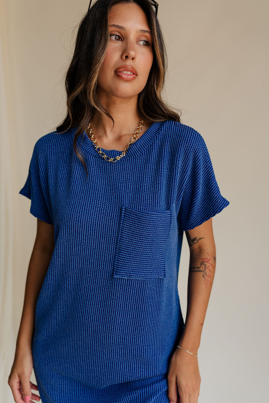 close up view of female model wearing the Elsie Ribbed Short Sleeve Mini Dress which features Ribbed Fabric, Mini Length, Left Front Chest Pocket, Short Sleeves and Round Neckline. the dress is available in black and blue.