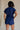 back view of female model wearing the Margot Tie Waist Short Sleeve Romper which features Elastic Waistband with Ties, Lightweight Fabric, V Neckline, Short Sleeves and Side Pockets. the romper is available in red and blue.