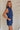 side view of female model wearing the Lila Navy Denim Button-Up Romper which features Navy Blue Washed Fabric, Two Front Pockets, Two Back Pockets, Front Zipper with Button Up Closure, Collared Neckline and Sleeveless