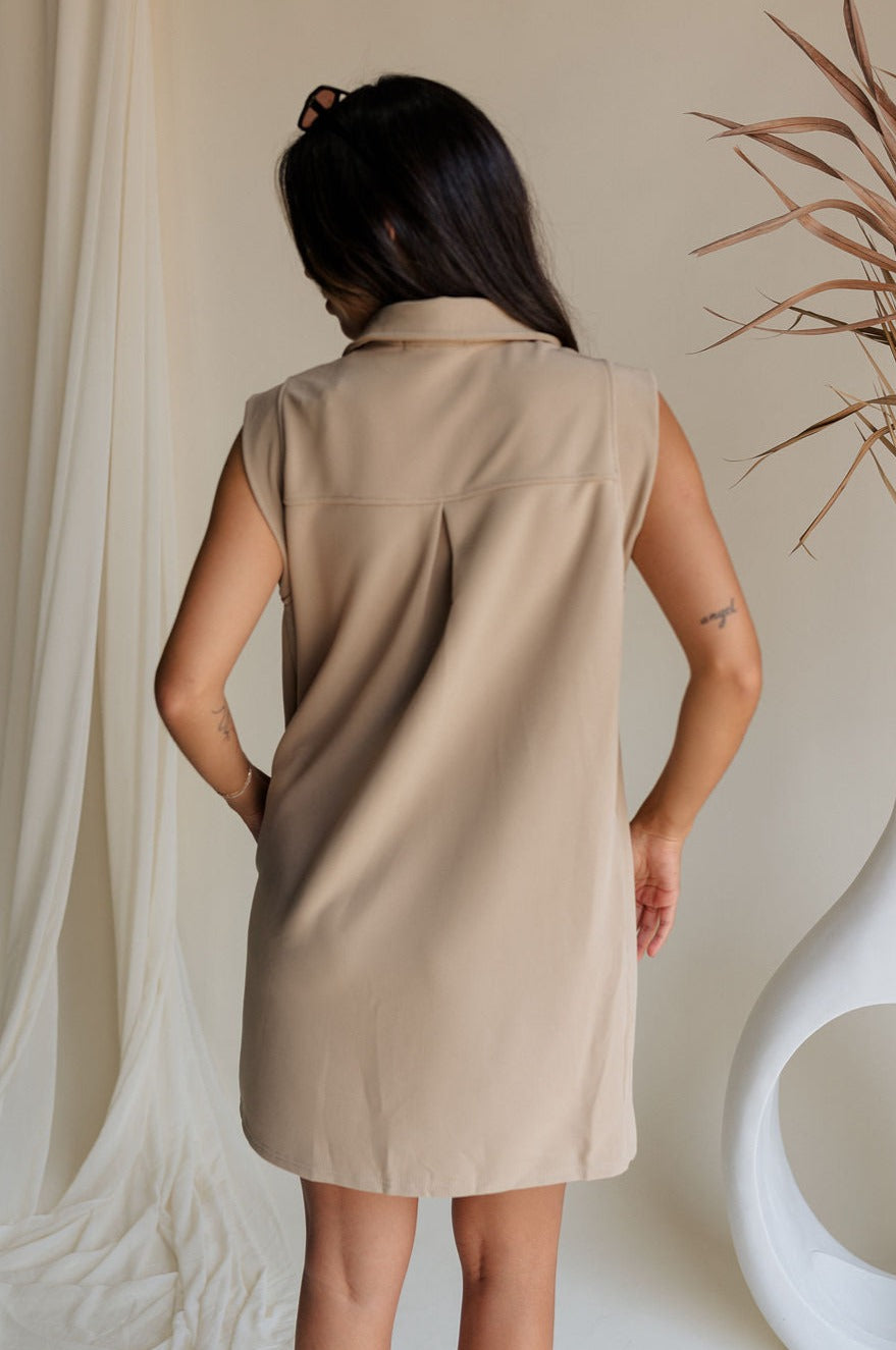back view of female model wearing the Lena Taupe Ribbed V-Neckline Mini Dress which features Light Taupe Ribbed Fabric, Two Side Pockets, V Neckline with Collar and Sleeveless