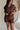 front view of female model wearing the Thea Brown Ribbed Shorts which features Brown Ribbed Fabric, Two Side Pockets, Elastic Waistband with Drawstring Tie and Gold Hardware Details