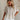 Upper body front view of female model wearing the Elysia Short Sleeve Ruffle Top that has cream fabric, ruffle details, front pleating, and slit sleeves with ties.